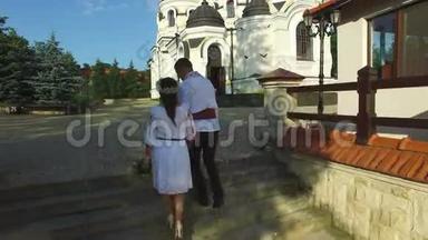 在婚礼当天，一对美丽的夫妇走上楼梯的空中景色。 穿着传统西装的新婚夫妇
